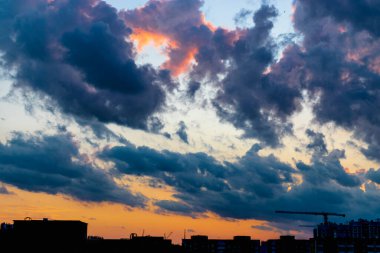 Günbatımı gökyüzünün arka planında inşaat halindeki vinç ve binaların siluetleri. Arka ışık. Modern bir şehirde büyük bir inşaat alanı