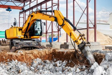 Endüstriyel hidrolik çekiç ve kazıcı kullanılarak güçlendirilmiş beton yapıların profesyonel yıkımı. Metal alaşımlı çubuklar. Beton enkazı ve kırıntıları