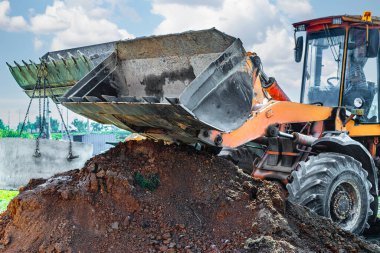 Kazı makinesinin hidrolik piston sistemi çelik kablolardaki beton kanalizasyon şebekesinin çukuruna iniyor. Kanalizasyon evinin inşaatı veya onarımı