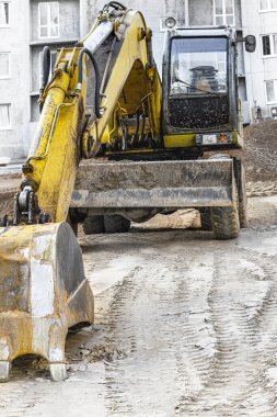 Büyük bir kova ile ağır bir sürüngen kazıcısı inşaat halindeki bir panelin önünde çalışmaya hazırlanıyor. Toprak işçiliği için ağır inşaat malzemeleri. Taş ocağı kazıcısı
