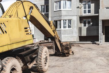 Büyük bir kova ile ağır bir sürüngen kazıcısı inşaat halindeki bir panelin önünde çalışmaya hazırlanıyor. Toprak işçiliği için ağır inşaat malzemeleri. Taş ocağı kazıcısı