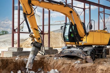 Endüstriyel hidrolik çekiç ve kazıcı kullanılarak güçlendirilmiş beton yapıların profesyonel yıkımı. Metal alaşımlı çubuklar. Beton enkazı ve kırıntıları