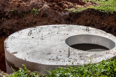 Installation of concrete sewer wells in the ground at the construction site. The use of reinforced concrete rings for cesspools, overflow septic tanks. Improvement of wells and storm sewage clipart