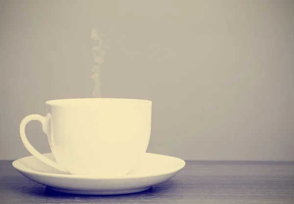 White cup and saucer on wooden table with retro filter effect — Stock Photo, Image