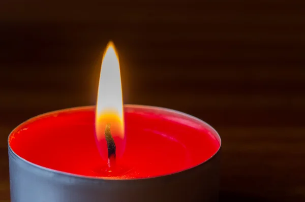 Dunkel glühendes rotes Teelicht auf Holztisch — Stockfoto