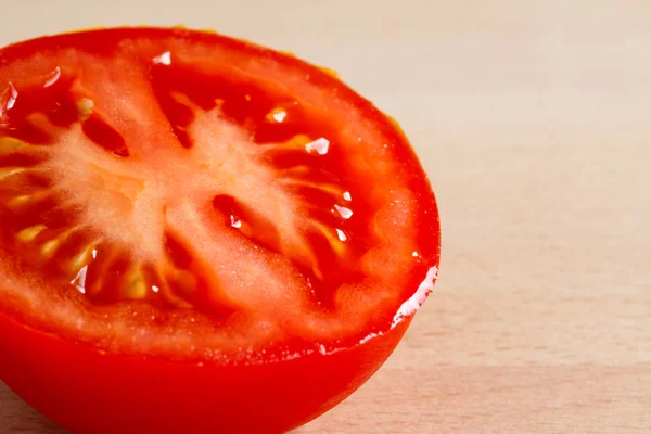 La moitié d'une tomate mûre rouge sur une planche de bois — Photo
