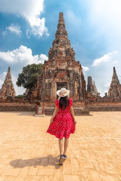 Asian tourist woman in red dress and sun hat from back view, walking through the beautiful history castle and historic temple at Ayutthaya, Thailand during vacation. travel after coronavirus lockdown