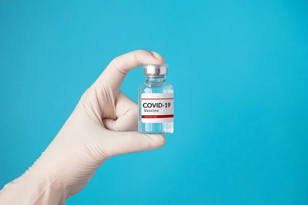Coronavirus Covid 19疫苗和免疫概念 用白色手套盛放注射用疫苗瓶 用蓝色背景隔离 供医疗用 大流行期间的化验室药检 — 图库照片