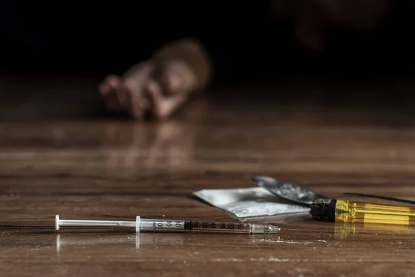 瘾君子 瘾君子问题的概念 把毒品注射器和煮熟的海洛因放在地板上 吸毒者的手从黑色背景伸出来 — 图库照片