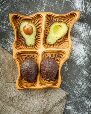 Durgun bir hayat ve yarım bir avokado ile ahşap tabakta