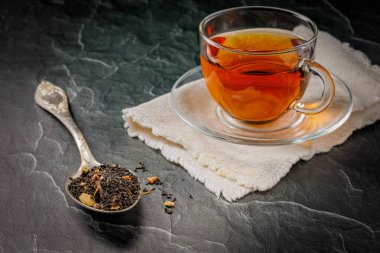 Bir kaşık siyah çay ve koyu arkaplanda siyah çay.