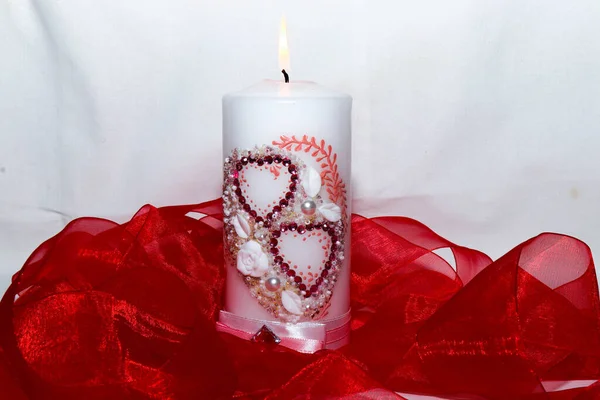 Isolated candle with hearts. Red ribbon. A burning candle. A bright flame. Decorative candle