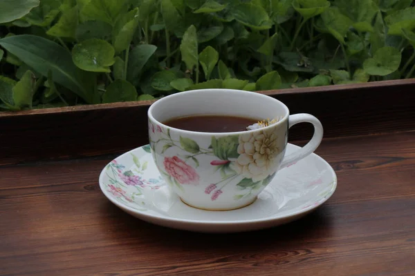 A cup of tea and spring flowers. Flower tea on a wooden tray. Tea drinking in the spring.