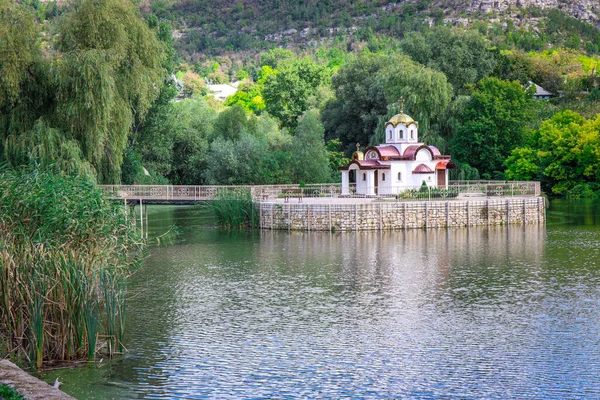A church on the water in a small village. A small temple located on an island in a lake.