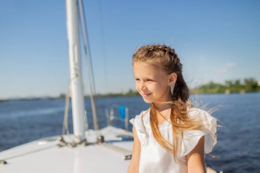 Güzel küçük kız yatta dikilirken gözlerini kaçırıyor.