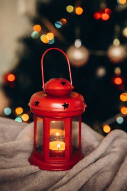 Noel ağacının arka planında kırmızı renkli kırmızı bir Noel feneri ve çelenkleri. Yeni yıl ve Noel konsepti. Dikey çerçeve