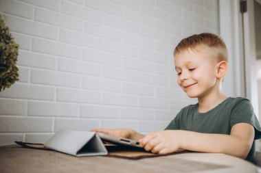 Çocuk mutfaktaki tablette bilgisayar oyunları oynuyor..