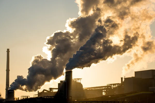 Puesta de sol en fábrica de acero mostrando chimeneas de humo — Foto de Stock