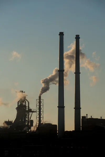 Puesta de sol en fábrica de acero mostrando chimeneas de humo — Foto de Stock
