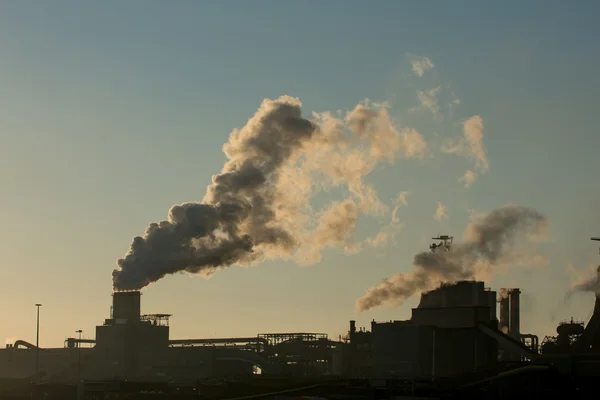 Puesta de sol en fábrica de acero mostrando chimeneas de humo — Foto de Stock