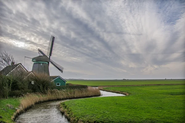 Velho moinho de vento holandês com céu ventoso — Fotografia de Stock