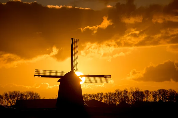 Moinho de vento holandês retroiluminado durante o nascer do sol — Fotografia de Stock