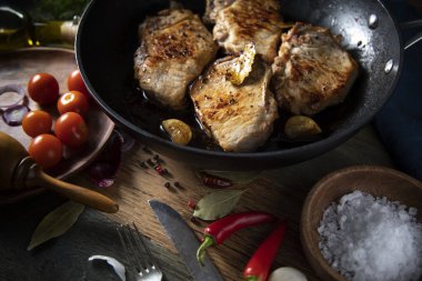 Dökme demir bir tavada kızarmış et ve kırsal bir masada sebzeler.