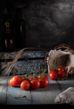 Tahta bir masanın üzerine su damlalarıyla kaplı kırmızı kiraz domatesleri.