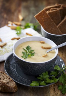 Çorba. Tahta bir masada gri bir fincanda patates püresi.