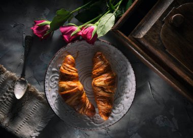 Taze kruvasan ve güller masada.