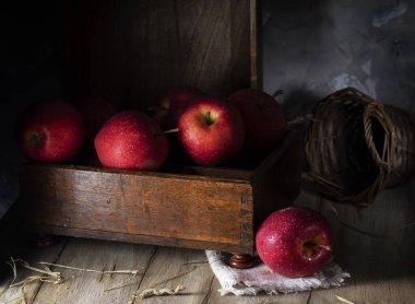 Kırsal masada kırmızı elmalar ve tahta kutu.