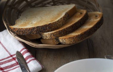 Kırsal bir masada sepette haşhaş tohumlu kızarmış buğday ekmeği.