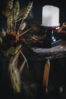 Eski ahşap bir masada, cam bir şamdanda mum.