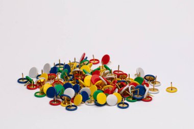 Beyaz arka plana saçılmış renkli raptiyeler.