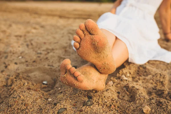 Women's feet on the yellow sand by the sea. The concept of travel
