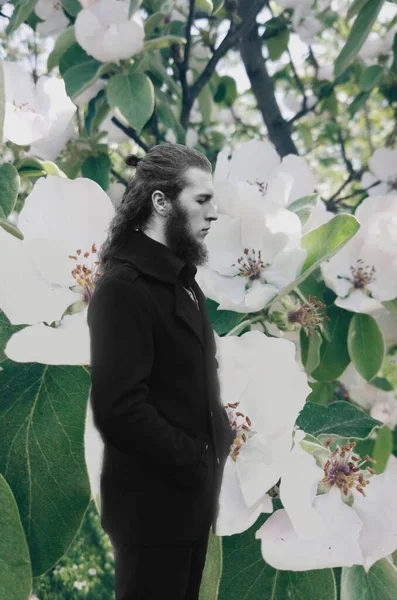 Мужской портрет на открытом воздухе в окружении цветущих цветов. — стоковое фото