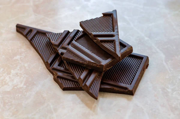 Chocolate bar pieces on marble table — Stock Photo, Image