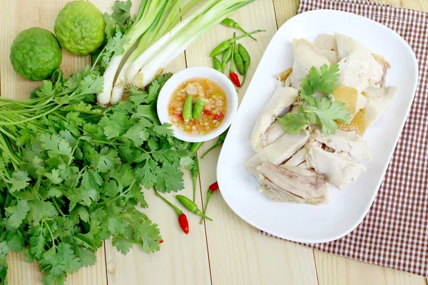 Temiz, beyaz tabağına pişmiş tavuk ve metin için yer ile ahşap üzerine yerleştirilen baharatlı sos yemek