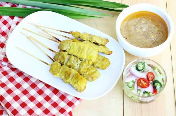 Domuz eti satay ahşap arka plan üzerinde beyaz plakaları