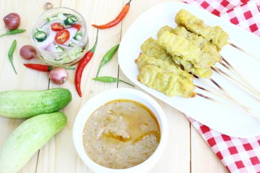 Domuz eti satay salatalık, kırmızı soğan ve biber ahşap bir masa üzerinde beyaz plaka koymak