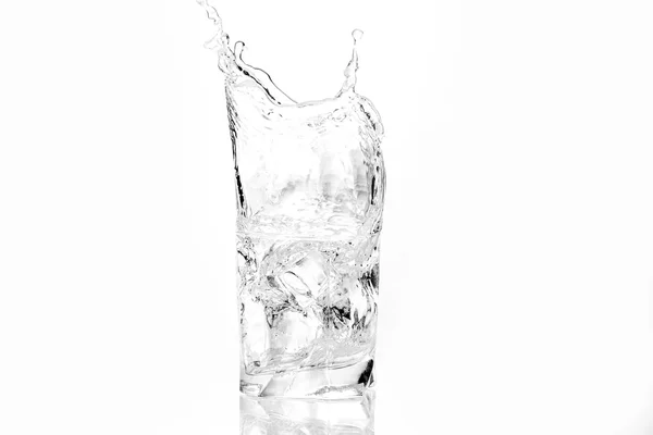 Cubos de gelo salpicando em vidro de água — Fotografia de Stock