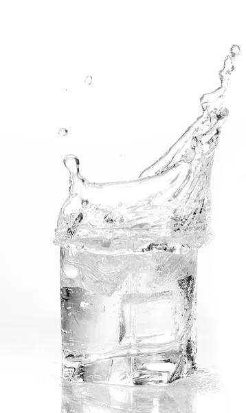 Kostki lodu rozpryskują się w szklance wody. — Zdjęcie stockowe