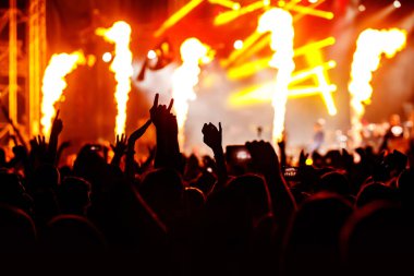Konserde kalabalık. Eller ve akıllı telefonlar sahnenin önünde.
