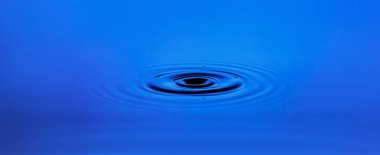 Mavi suyun yüzeyinde dairesel dalgalar.