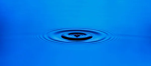 Kruh vlnění na povrchu modré vody. — Stock fotografie