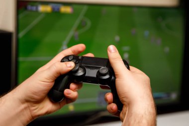 Evde bilgisayar ya da futbol oynayan bir adam. Konsol denetleyici elinde.