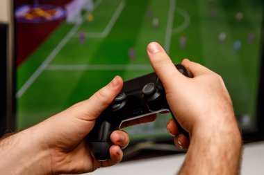 Evde bilgisayar ya da futbol oynayan bir adam. Konsol denetleyici elinde.