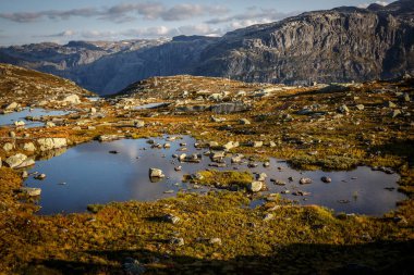 Gün batımında küçük gölleri olan dağ manzaraları vadisi. Norveç 'te trolltunga' ya giden yol
