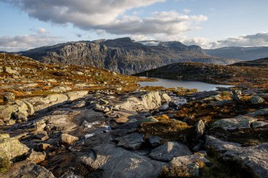 Gün batımında küçük gölleri olan dağ manzaraları vadisi. Norveç 'te trolltunga' ya giden yol