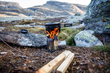 Bir dağ kampında küçük bir kamp ocağında yemek pişirmek.